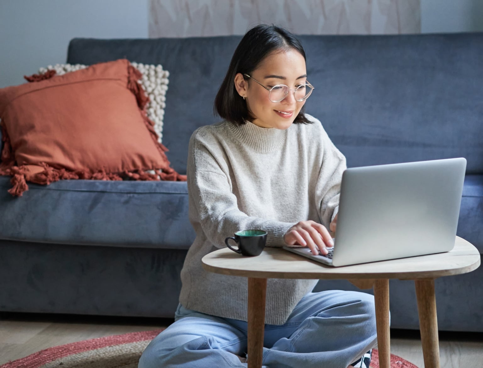 femme assise au sol devant un pc portable